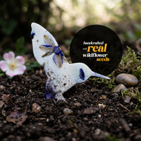 Small bird statue with "handcrafted by real wildflowers" text, part of Hummingbird Memorial Plantable Seed Paper