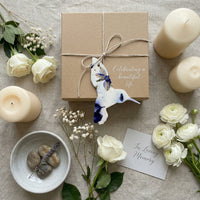 A person presents a card alongside a butterfly photo, highlighting Hummingbird Memorial Plantable Seed Paper