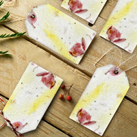 Scattered Pink and Yellow Plantable Seed Paper Blank Gift Tags by Seed Bloom Gifts on a rustic wood table, showing the embedded pink petals and yellow coloring.