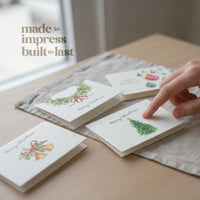 Handmade Plantable Christmas holiday cards by Seed Bloom Gifts with festive designs on a wooden surface.