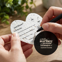 Seed bloom planting card with a hand holding a pen and a black circular component.