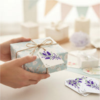 Seed paper gift tag with purple lavender botanical design attached to wrapped gift with twine bow, showing personalization