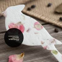A basket filled with plantable seed paper angel-shaped funeral favors decorated with pressed pink flowers