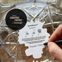 Seed bloom planting guide being filled out with a pen on a decorative glass plate.