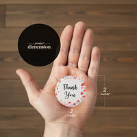 A hand holds a 2-inch "Thank You" button, part of Bloom Thank You Tags collection