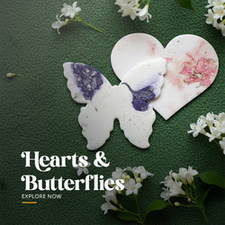 Plantable seed paper heart favor embedded with pink petals shown overlapping a butterfly favor embedded with purple petals, illustrating a mixed set of shapes by Seed Bloom Gifts