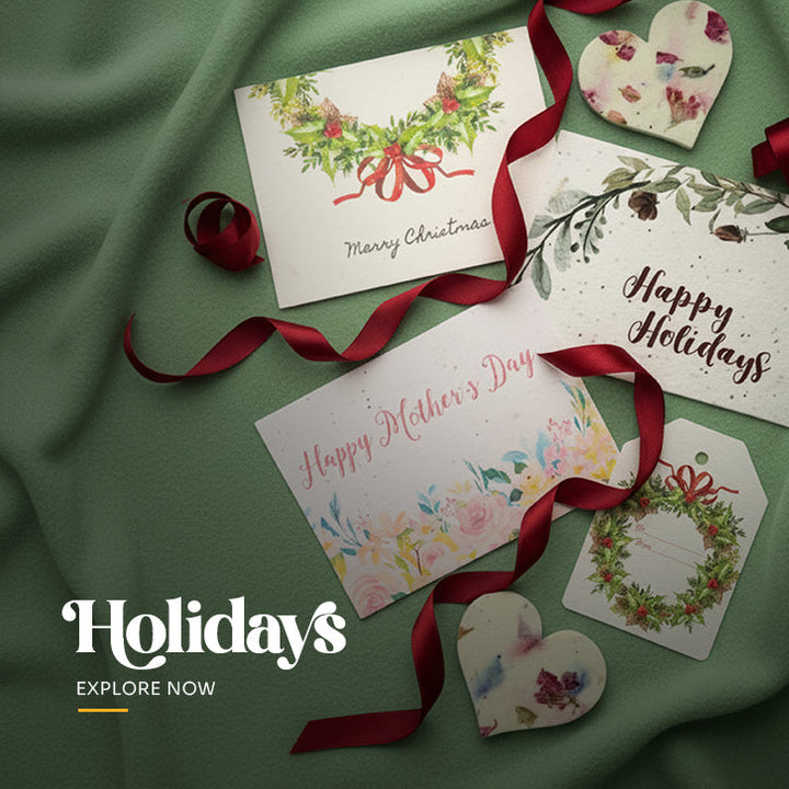 Collection of five plantable seed paper holiday cards featuring assorted designs, including Christmas bells, a festive wreath, a cardinal on a pine branch, and colorful ornaments by Seed Bloom Gifts