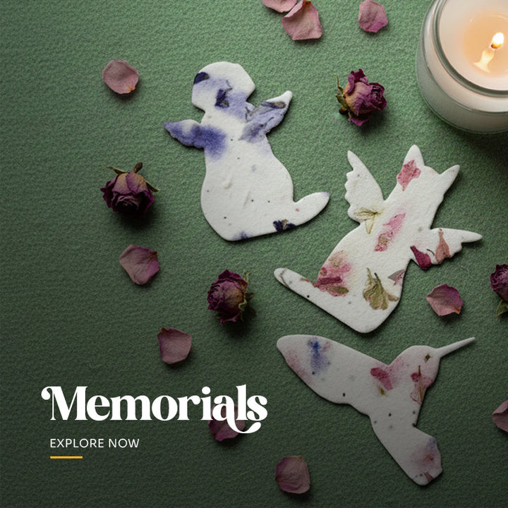 Plantable seed paper pet memorial favor cut into the shape of a seated cat with angel wings, embedded with visible pink and green wildflower petals by Seed Bloom Gifts