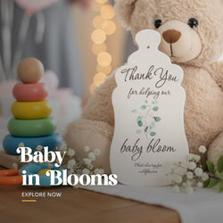 Plantable seed paper baby shower favor cut in a onesie shape, printed with 'Thank You for helping our baby bloom' text and blue flowers, shown with planting instruction card by Seed Bloom Gifts