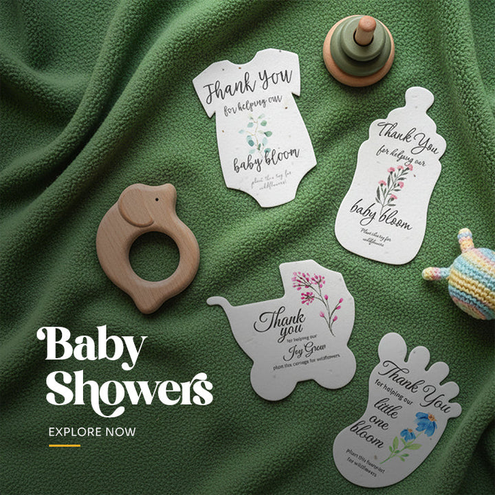 Plantable seed paper baby shower favor cut in a onesie shape, printed with 'Thank You for helping our baby bloom' text and blue flowers, shown with planting instruction card by Seed Bloom Gifts