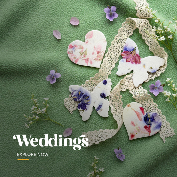 Plantable seed paper wedding favor cut in a heart shape, featuring large embedded pink and yellow dried flower petals and visible texture by Seed Bloom Gifts