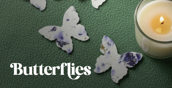 Butterfly-shaped  Seed paper with candles on a green surface with a candle in the background.