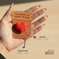 Hand holding a plantable 3D heart seed paper gift on an illustrated message card, showing heart and card size measurements