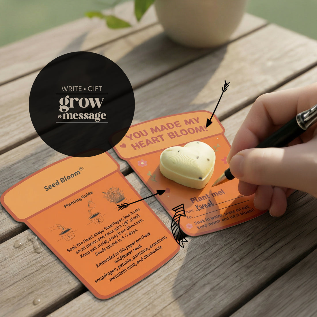 Person writing a message on a 3d plantable heart seed paper gift card placed on a wooden table
