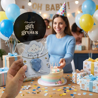 Baby in Bloom baby boy onesie seed paper "gift that grows" - woman presenting light blue favor at colorful OH BABY celebration with blue and yellow balloons, confetti, cake, and wrapped gifts