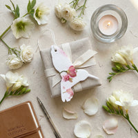 A person holds a small bird with a flower, highlighting the Hummingbird Memorial Plantable Seed Pape