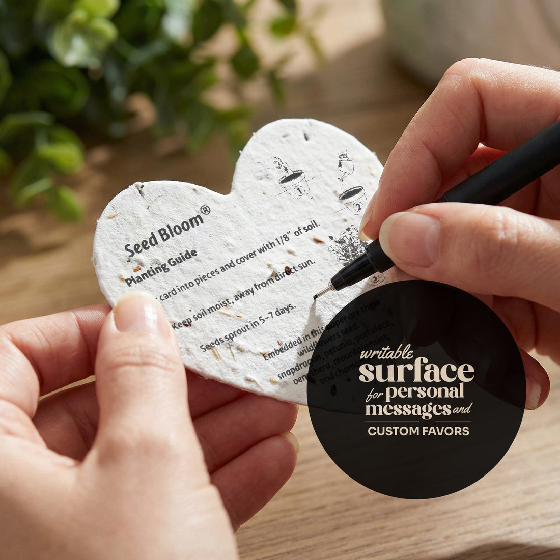 Seed bloom planting card with a hand holding a pen and a black circular component.
