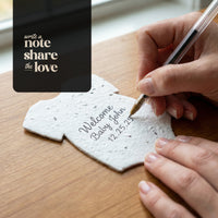 Person writing on a seed paper baby shower favor by Seed Bloom Gifts with text overlay 'Write a note, share the love'.
