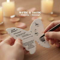 Butterfly-shaped seed planting guide with a hand holding a pen, set against a blurred candlelit background by Seed Bloom Gifts.