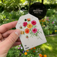 A hand displays a small tag with a flower, labeled "Bloom Thank You