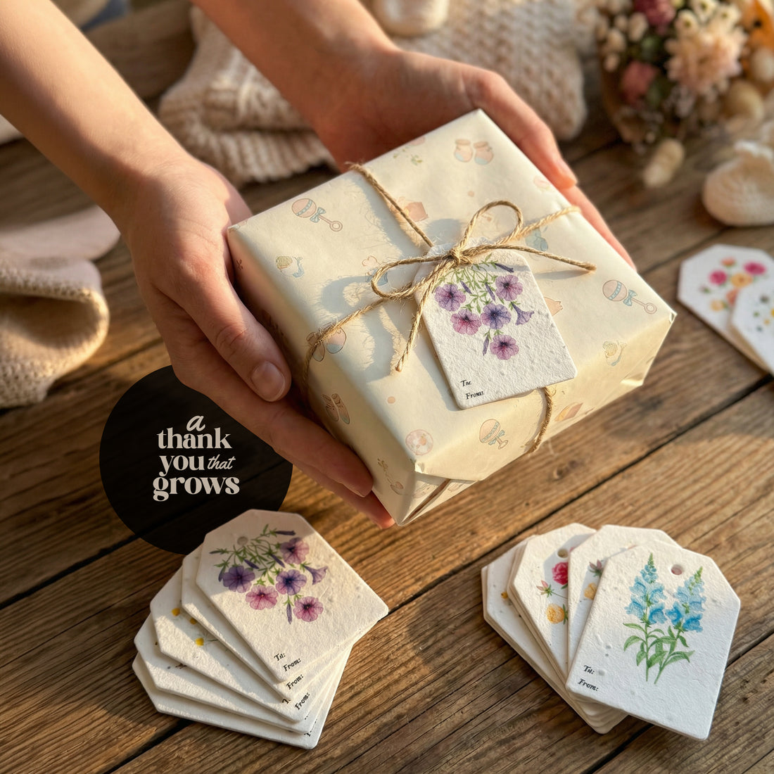 A hand holds a gift box with a small gift card labeled "Bloom Thank You Tags