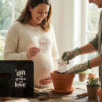 Bloom Plantable Seed Paper Baby Shower Kit onesie being planted in terra cotta pot with message 'a gift that grows with love