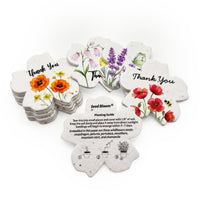 Seed Bloom scalloped thank you tags set with watercolor floral designs including orange poppies, purple lavender with butterfly, pink bell flowers, and red poppies with bee, displaying central flower-shaped planting guide with step-by-step instructions and list of wildflower seeds including snapdragon, petunia, and chamomile