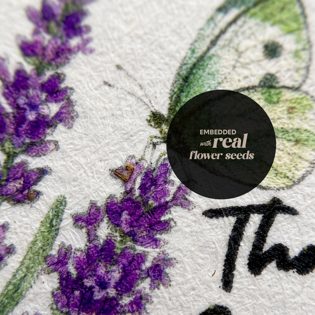 Close-up detail of seed paper thank you tag with watercolor purple lavender and butterfly design showing embedded wildflower seeds