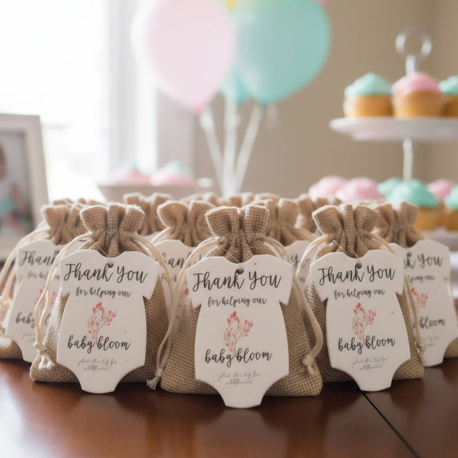 Burlap bags with pink onesie plantable seed paper baby shower favor by Seed Bloom Gifts tags at a baby shower event with balloons and cupcakes.