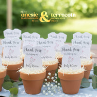 Terracotta pots with pink onesie plantable seed paper baby shower favors by Seed Bloom Gifts, and a blurred green outdoor background