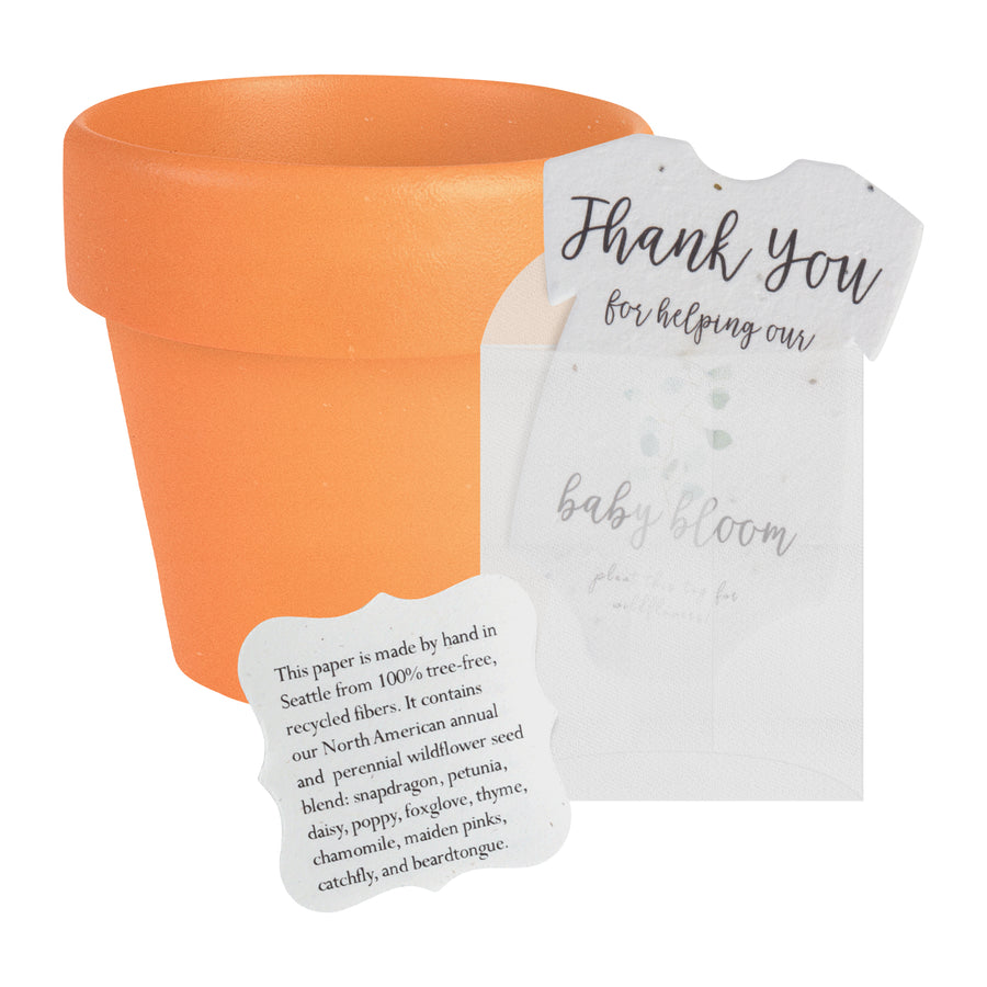 Small terracotta pot with a plantable gender neutral green onesie baby shower favor by Seed Bloom Gifts and a small card describing the wildflower seed blend. 