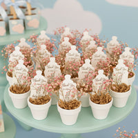 Decorative potted plants with 'Thank You' baby shower seed paper baby bottle by Seed Bloom Gifts on a green stand.