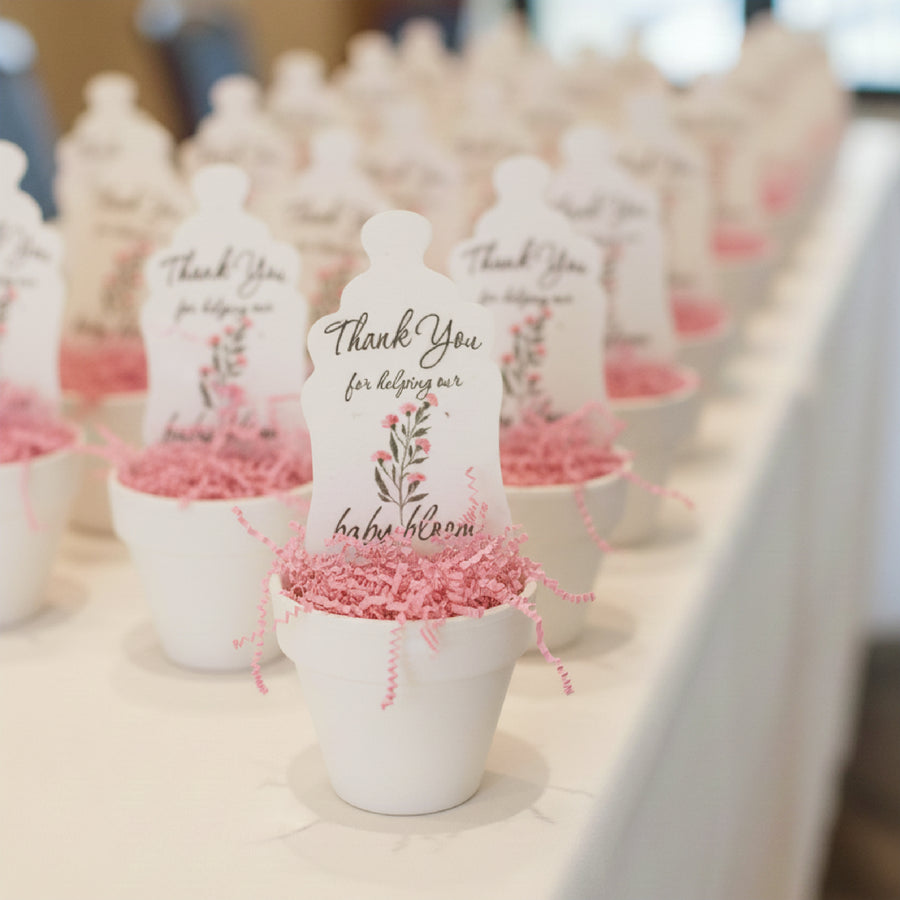 White teddy bears with 'Thank You' messages in small pots with baby bottle baby shower favor by Seed Bloom Gifts on a table.