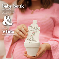 Person holding a white baby bottle-shaped  baby shower favor  seed paper by Seed Bloom Gifts with text and a small white pot.
