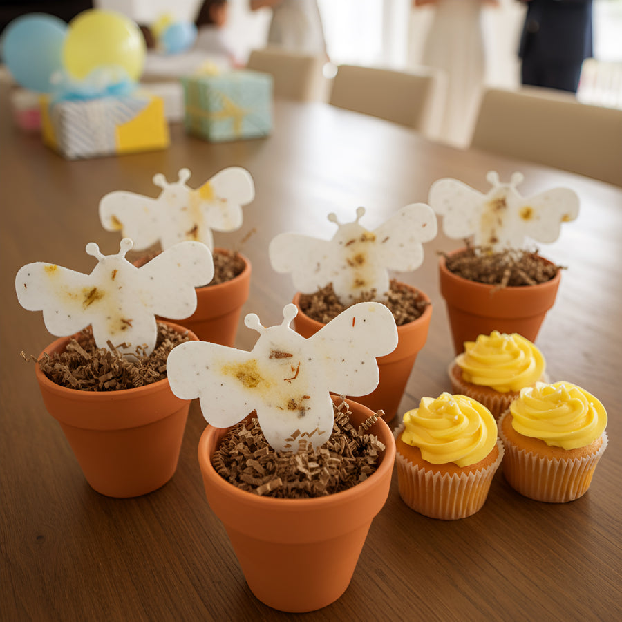 Bee Shaped Seed Paper Baby Shower Favor By Seed Bloom Gifts with cupcakes in small pots on a wooden table