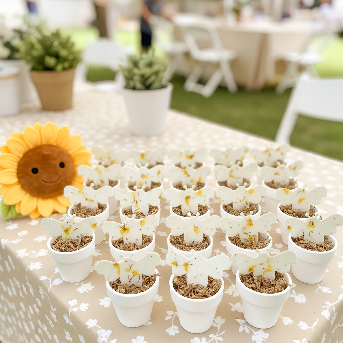 Table with small potted plants and a Bee Shaped Seed Paper Baby Shower Favor By Seed Bloom Gifts
