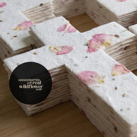 A paper cross adorned with pink flowers, designed as a plantable seed paper funeral favor