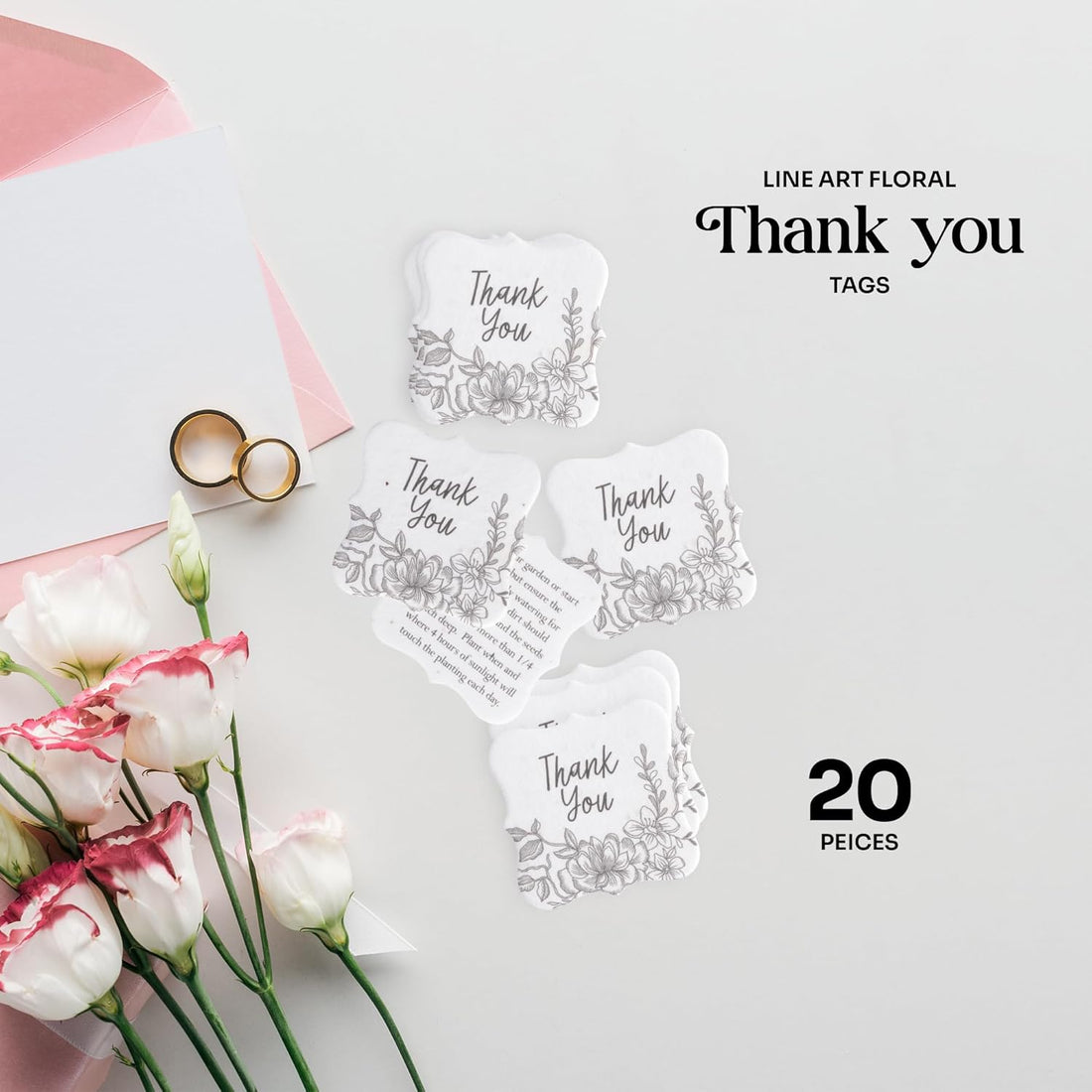 Styled flat lay showing 20 Pieces of Floral Plantable Thank You Seed Paper Tags by Seed Bloom Gifts with wedding rings, flowers, and a pink envelope.