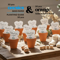 Set of 30 plantable seed paper onesie baby shower favors displayed in orange terracotta pots on a wooden table, including a planting guide, with each onesie reading “Thank you for helping our baby bloom
